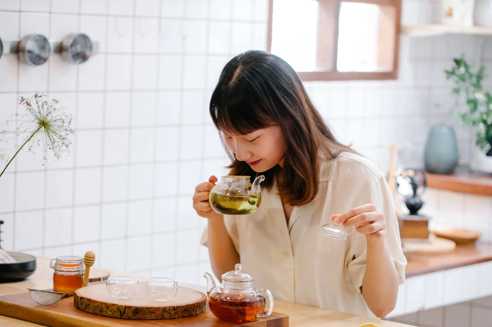Asian woman preparing herbal leaf tea — Photo: Anna Pou / Pexels
